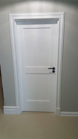 A white door with a black handle is in a hallway.