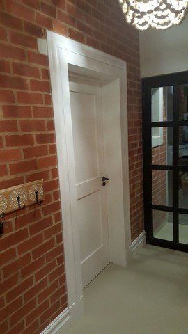 A hallway with a brick wall and a white door.