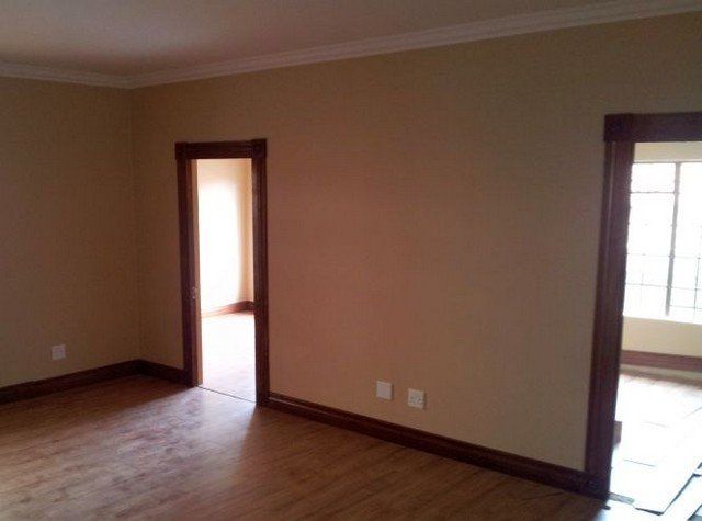 An empty room with hardwood floors and tan walls