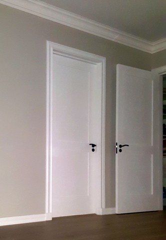 A room with two white doors and a wooden floor.