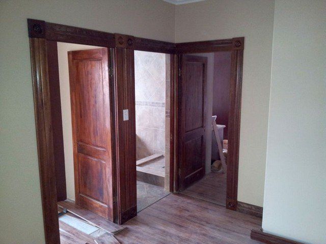 A hallway with wooden doors leading to a bathroom and stairs.