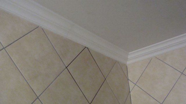 A corner of a room with tile floors and a white ceiling.