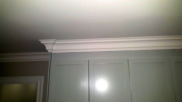 A white crown molding is on the ceiling of a kitchen.