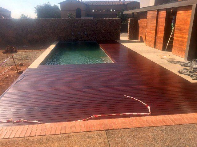 A swimming pool with a wooden deck in front of it