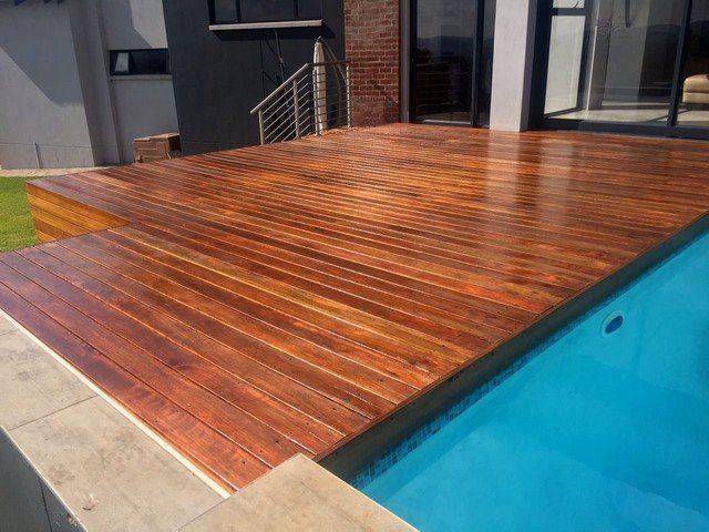 There is a wooden deck next to a swimming pool.