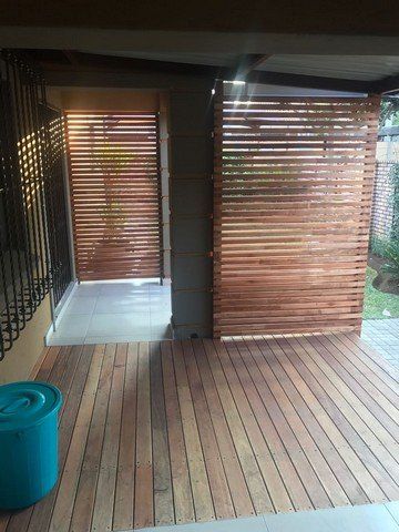 A wooden deck with a wooden fence and a blue bucket.