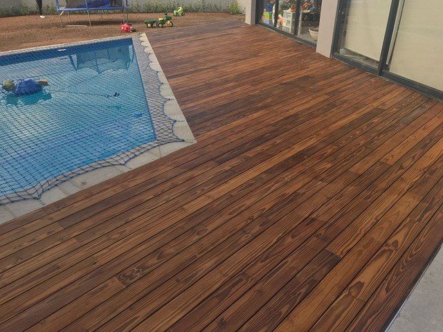 A wooden deck next to a swimming pool.