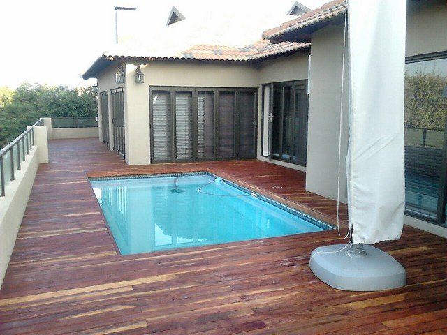 A large swimming pool is surrounded by a wooden deck