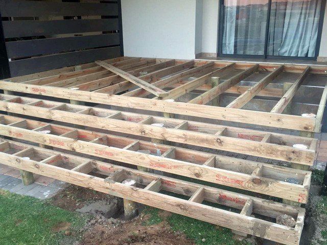 A wooden deck is being built in front of a house.