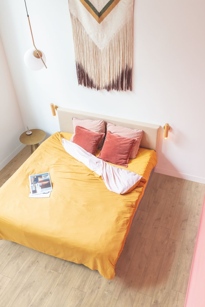 A bed with a yellow comforter and pillows in a bedroom.