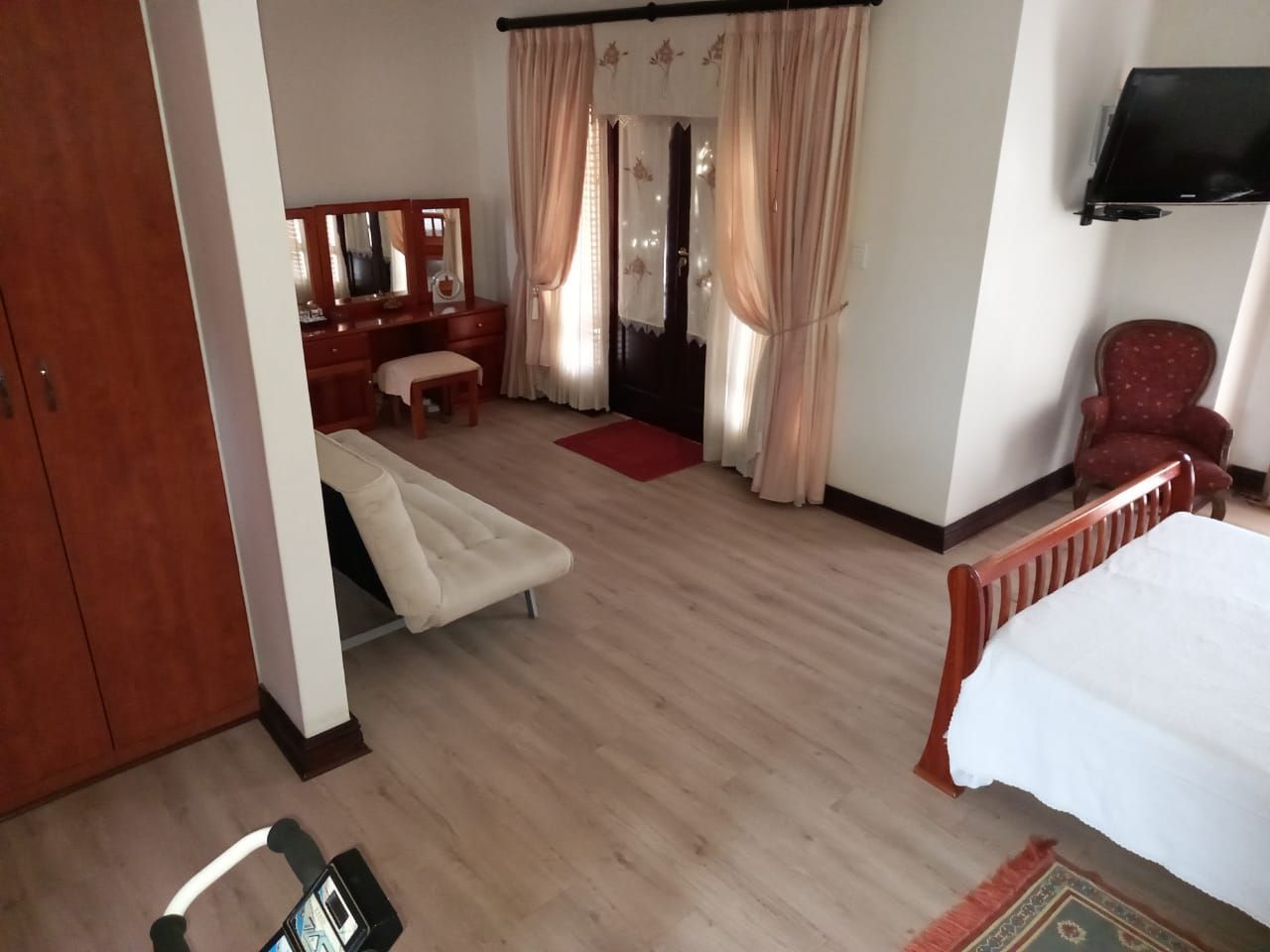 A bedroom with a bed a chair and a television