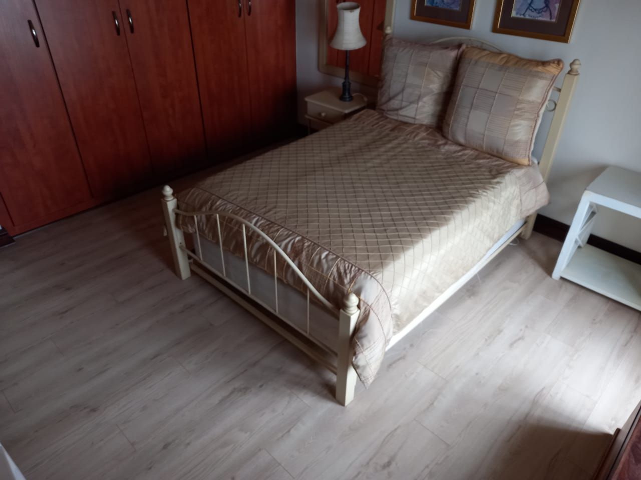 A bedroom with a bed a nightstand and a lamp