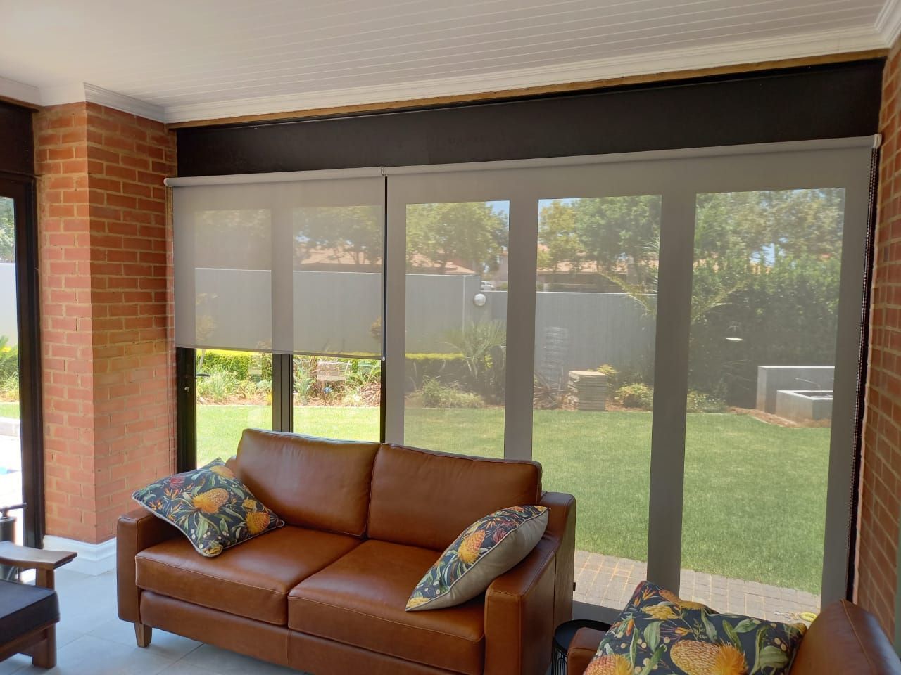 A living room with a brown couch and a lot of windows.