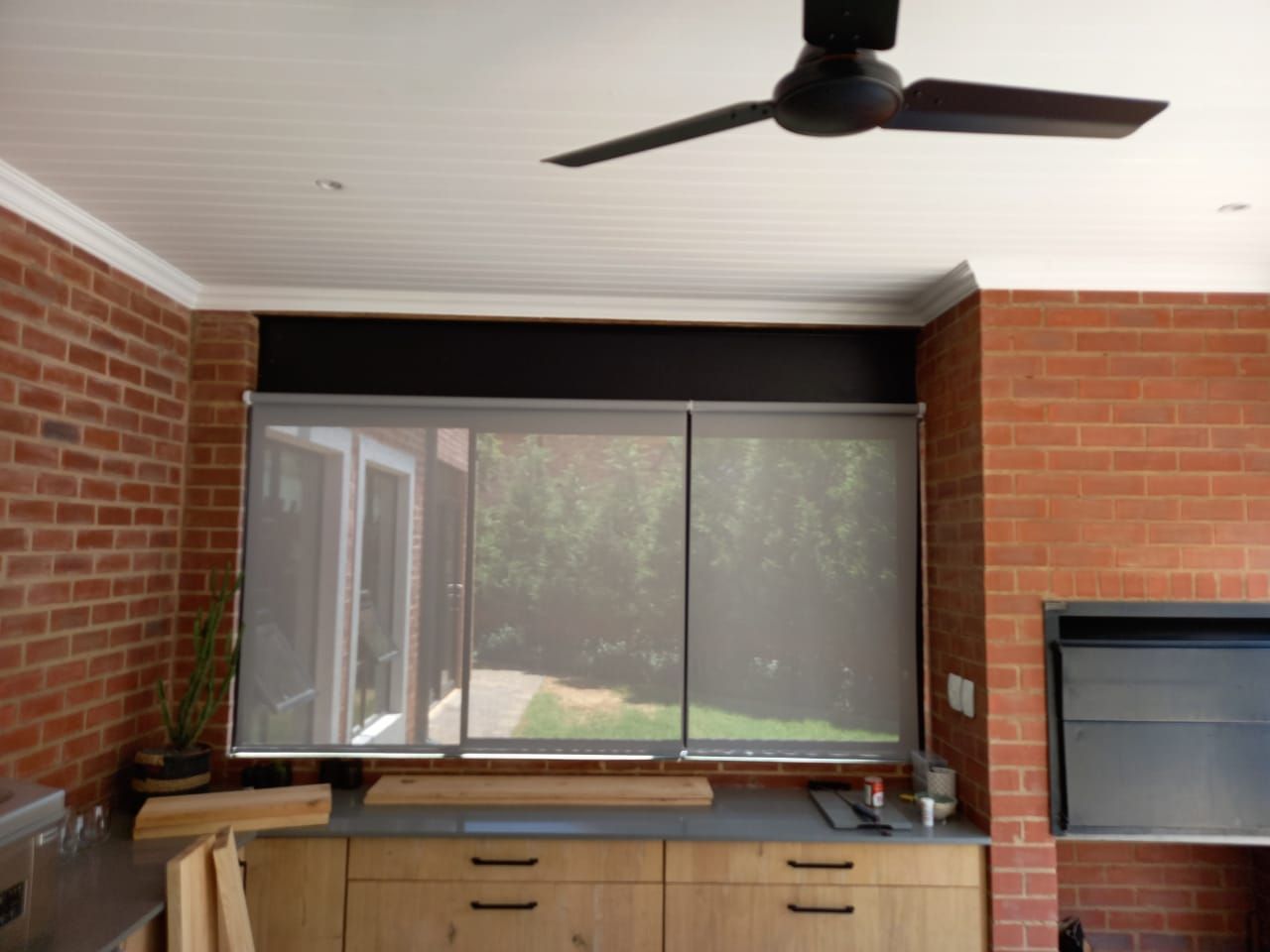 A kitchen with a ceiling fan and a brick wall