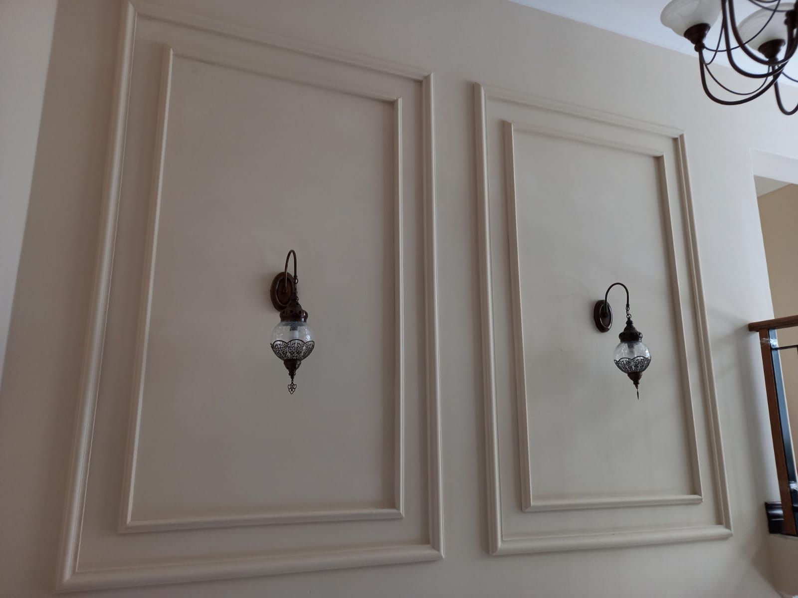 A wall with two lights on it and a chandelier hanging from the ceiling