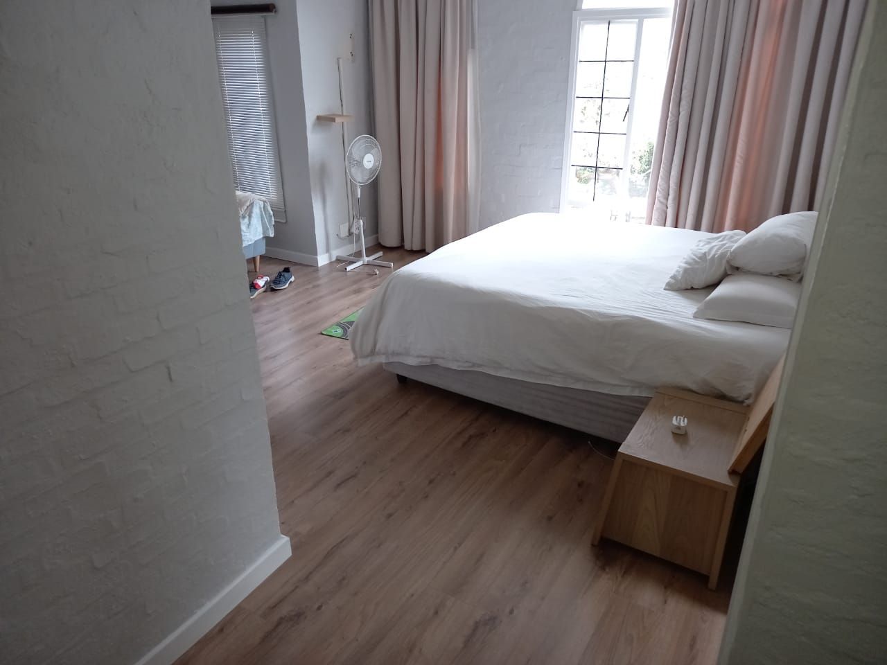 A bedroom with a bed , nightstand , and fan.