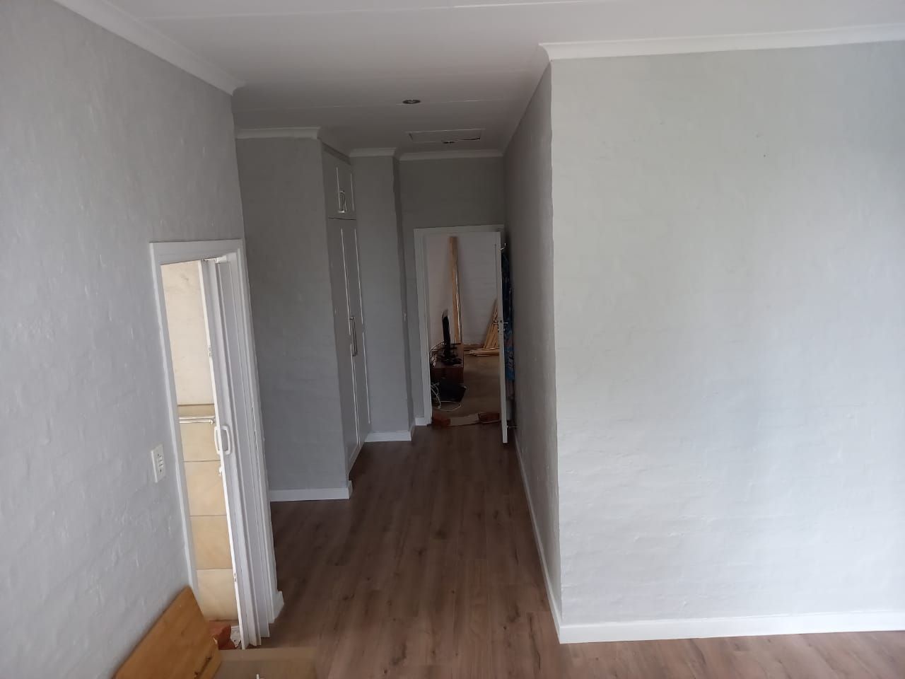 A hallway with a wooden floor and white walls