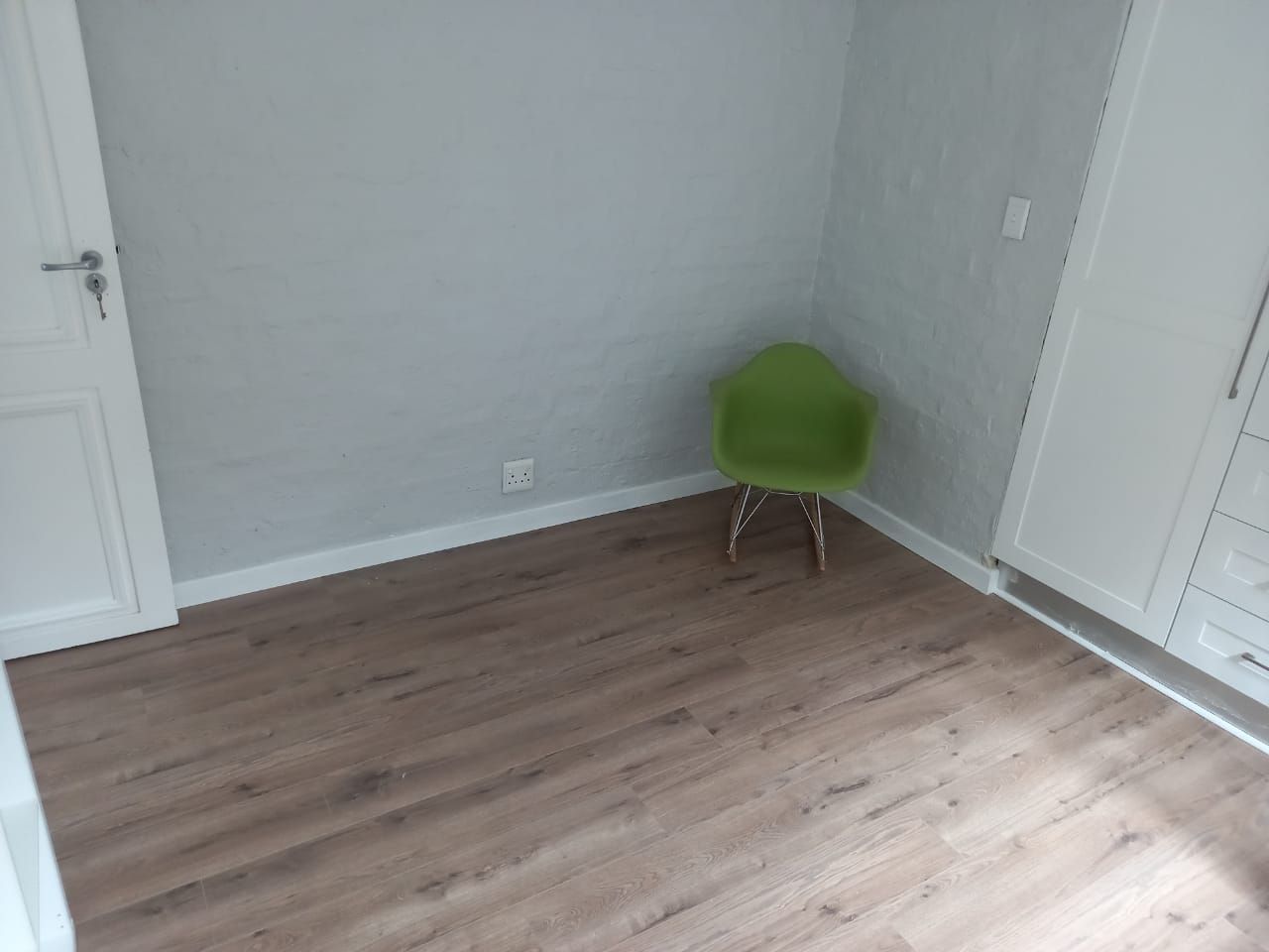 There is a green chair in the corner of the room.
