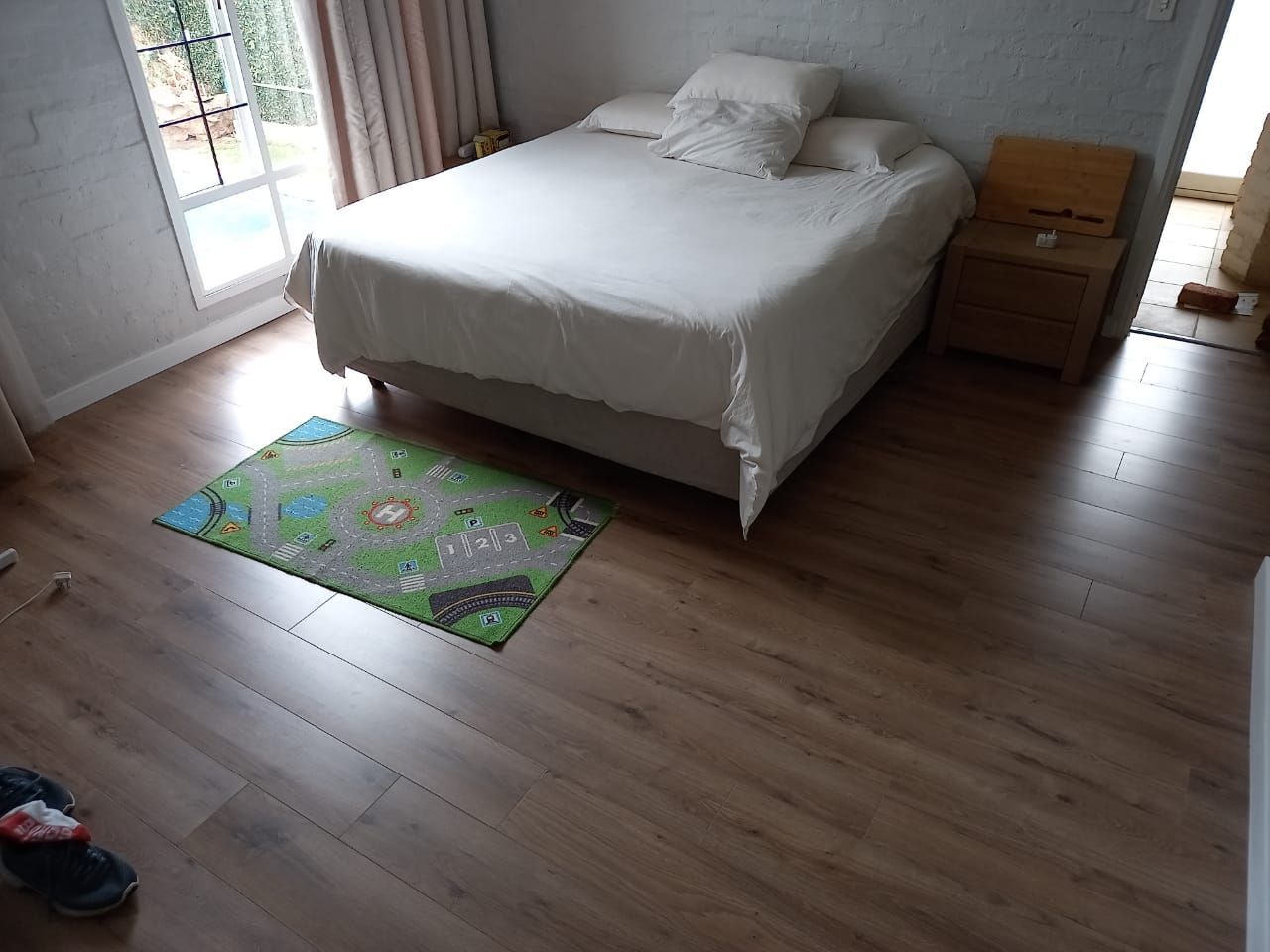 A bedroom with a bed and a rug on the floor.