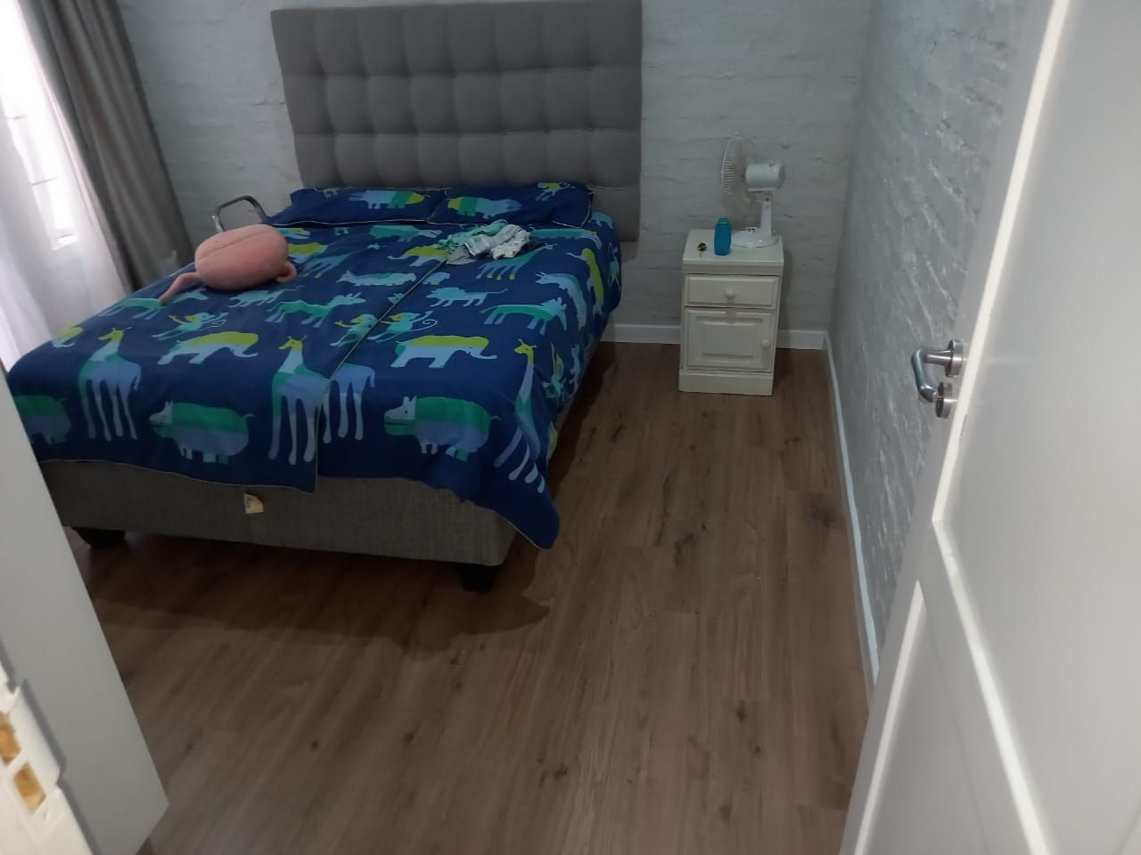 A bedroom with a bed , nightstand , and window.