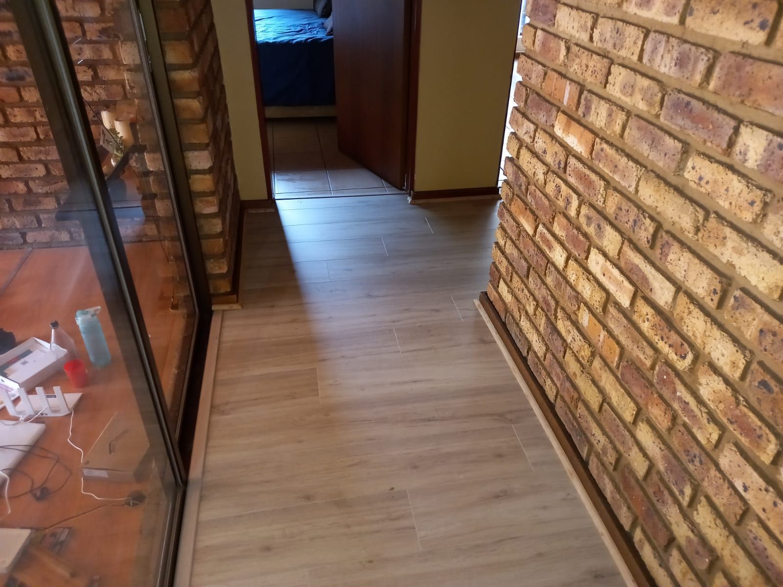 A hallway with a brick wall and a wooden floor