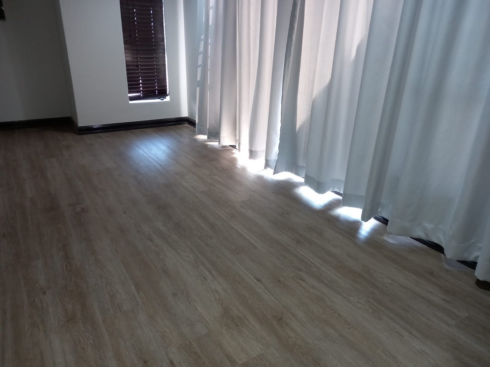 A room with a wooden floor and white curtains