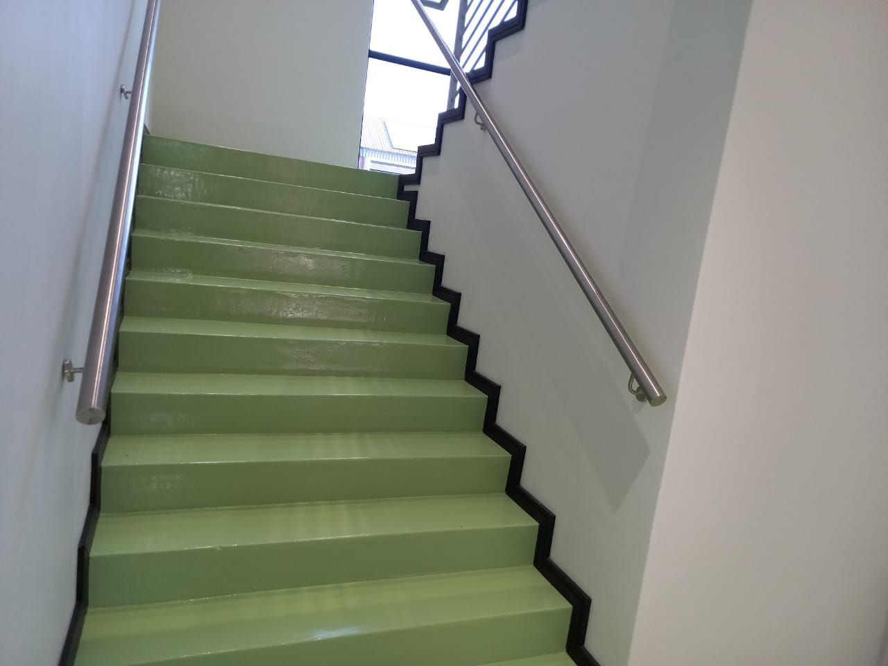 A set of green stairs with a stainless steel railing