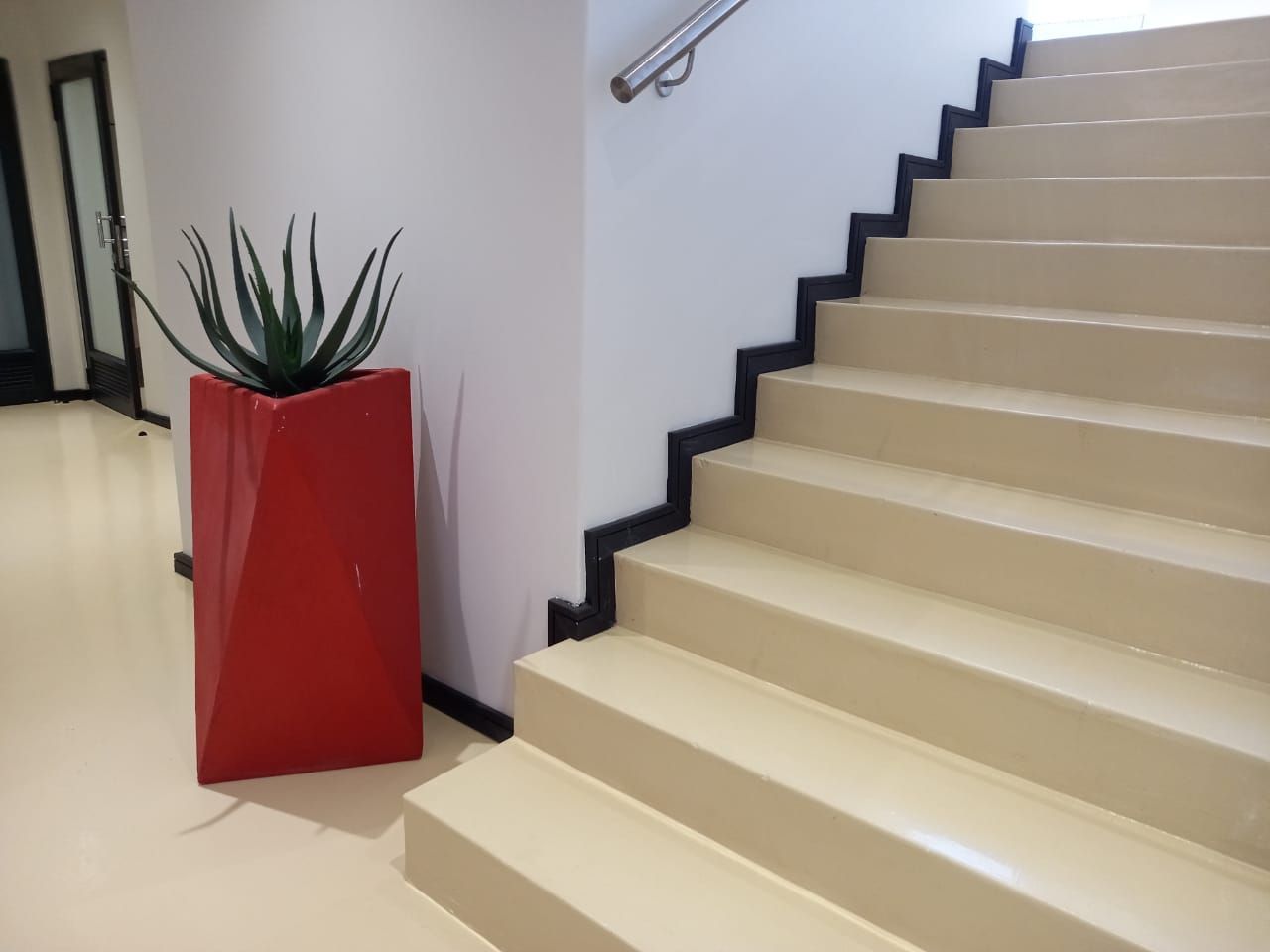 A red potted plant sits next to a set of stairs