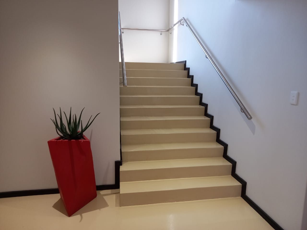A red potted plant sits next to a set of stairs