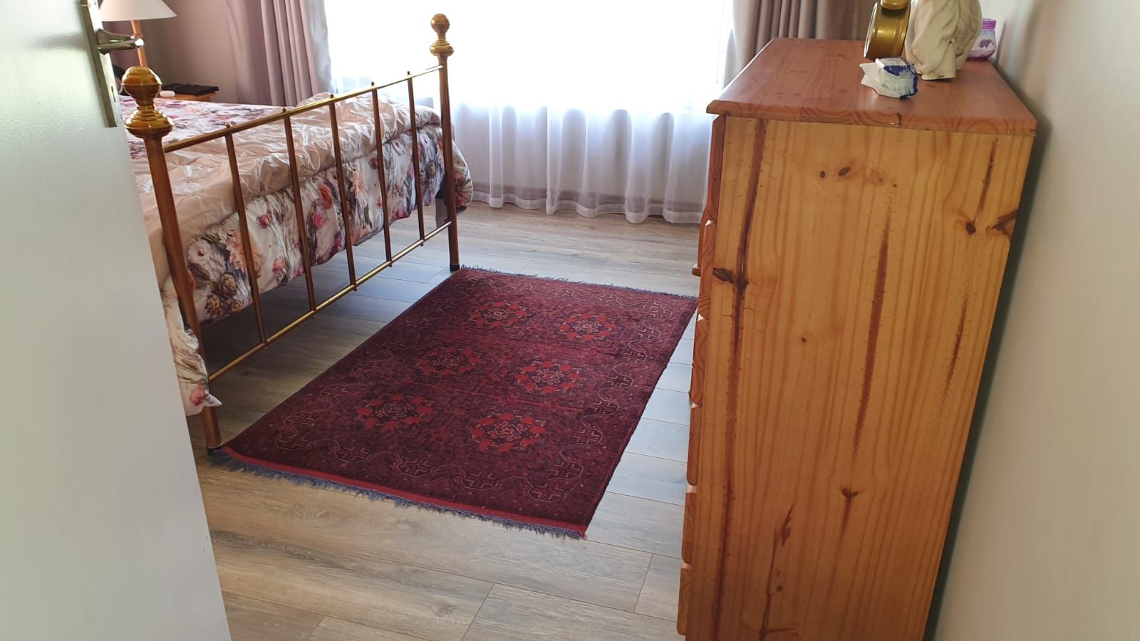 A bedroom with a bed , dresser , and rug.