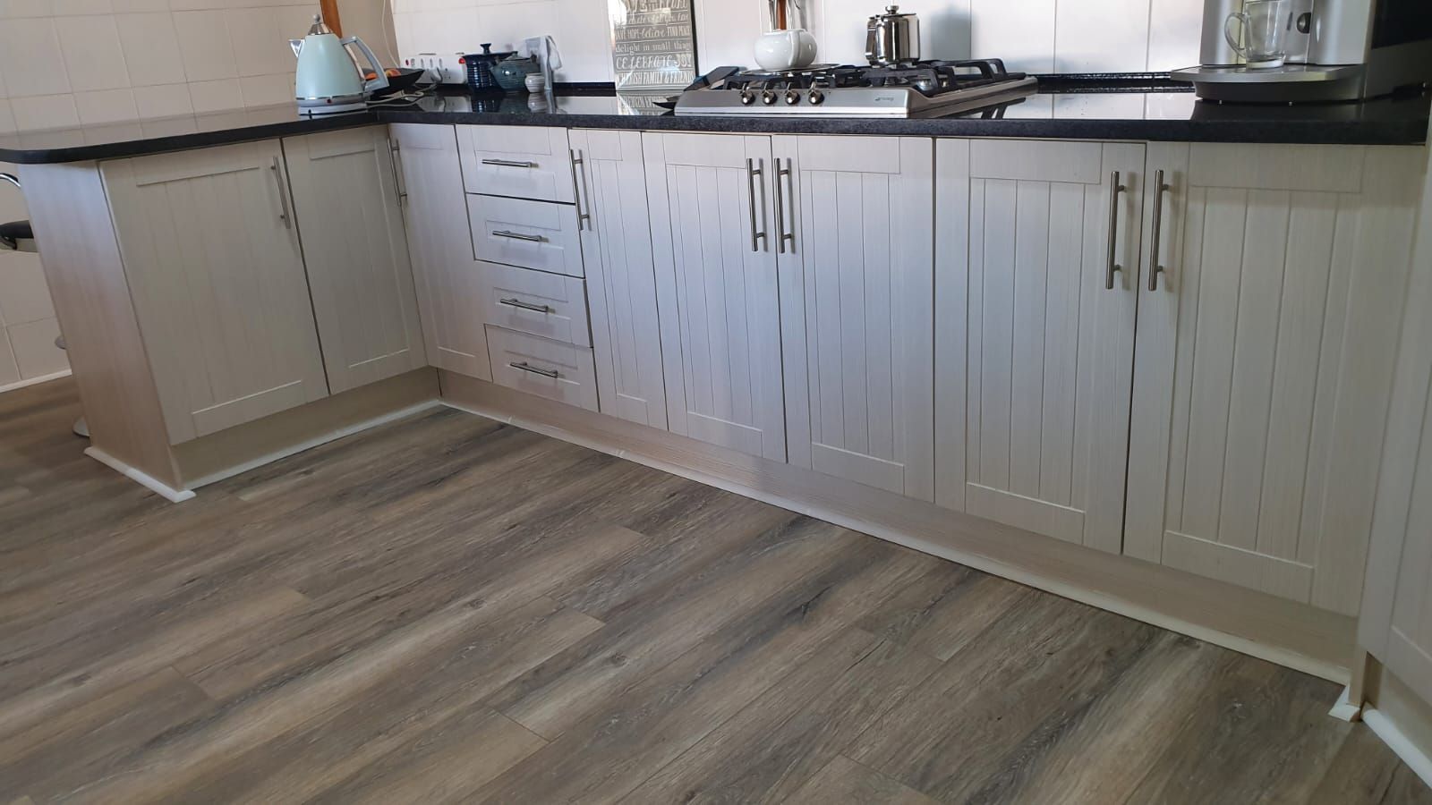 A kitchen with white cabinets and a wooden floor.