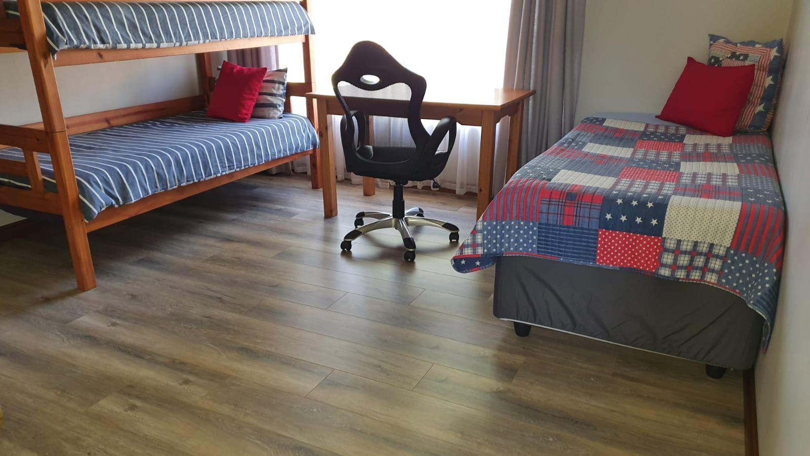 A bedroom with two bunk beds , a desk and a chair.