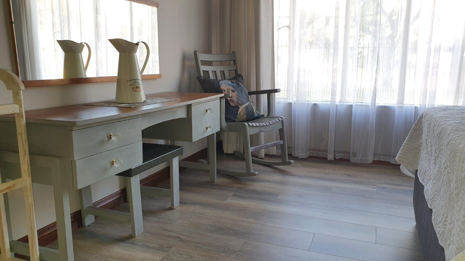A bedroom with a desk , chair , mirror and bed.