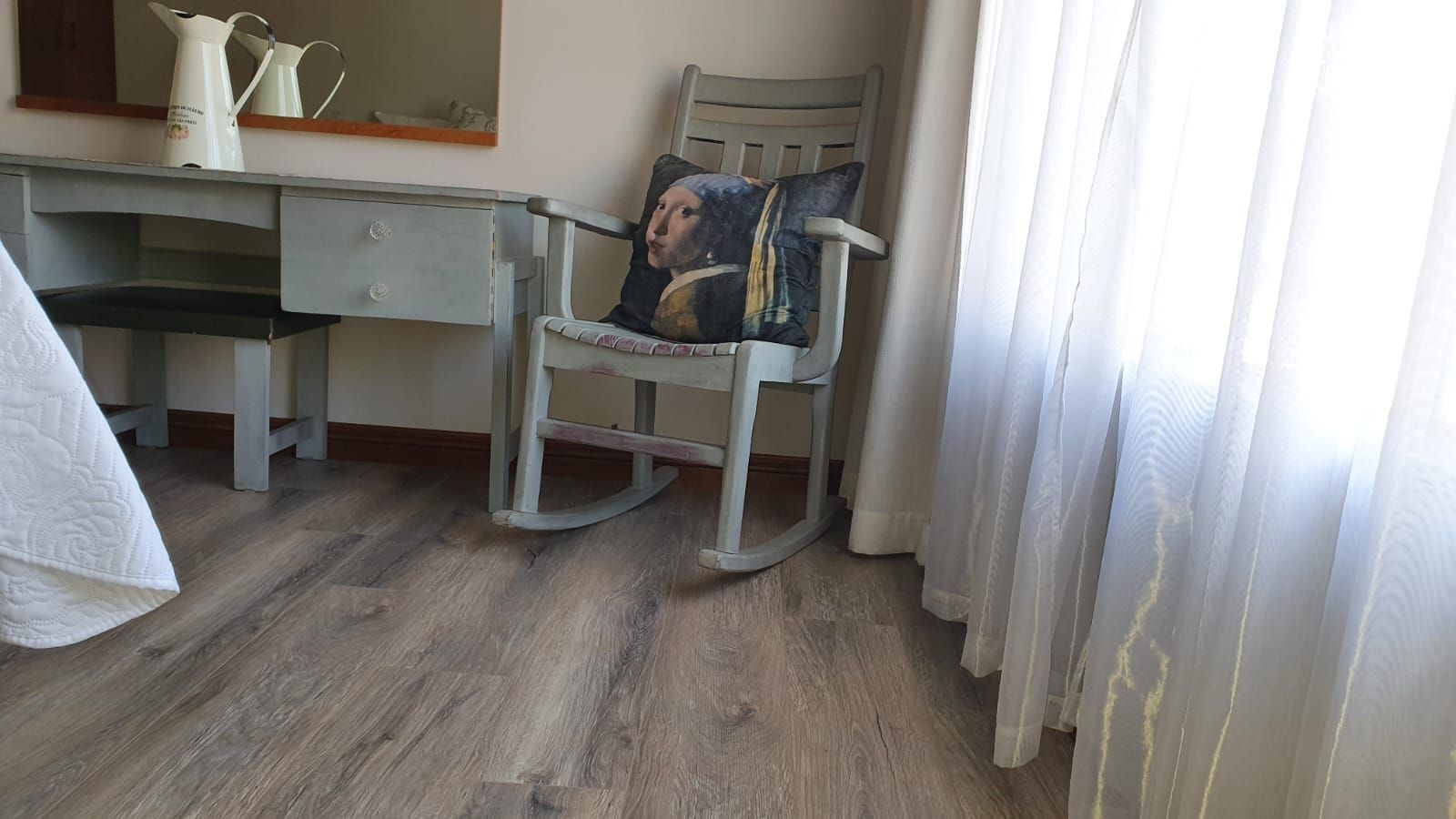 A rocking chair is sitting next to a desk in a bedroom.