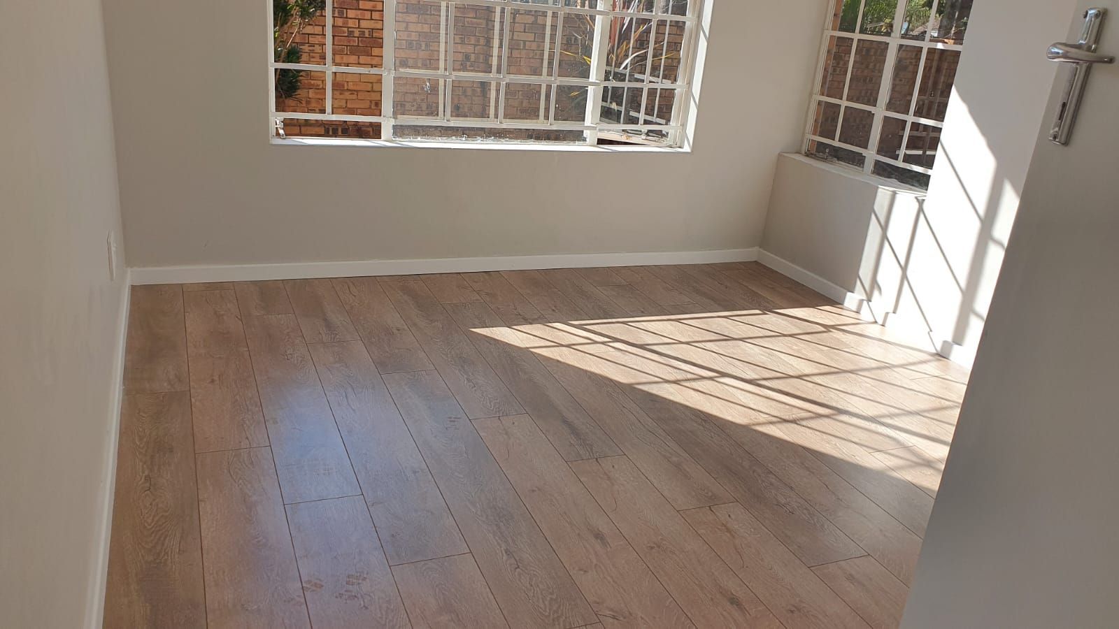 An empty room with a wooden floor and a window.