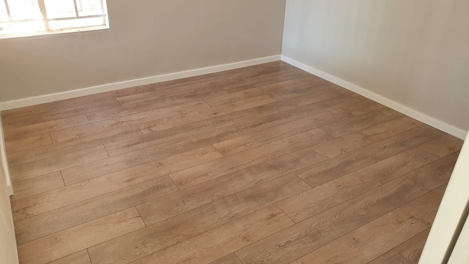 An empty room with a wooden floor and a window.