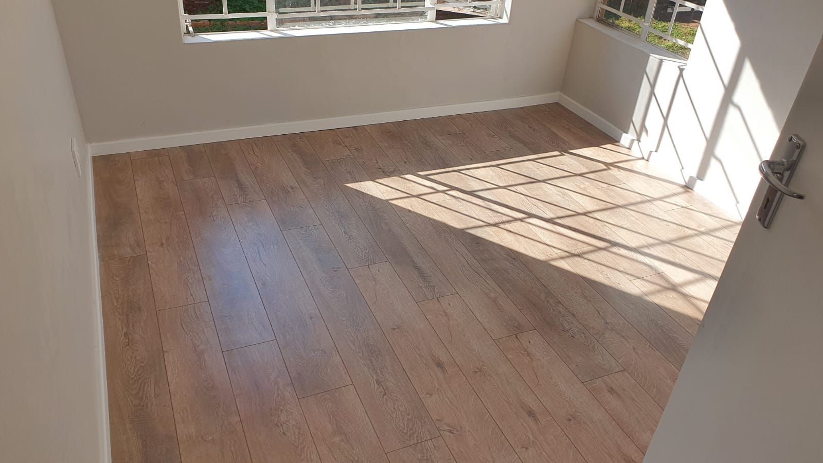 An empty room with a wooden floor and a window.