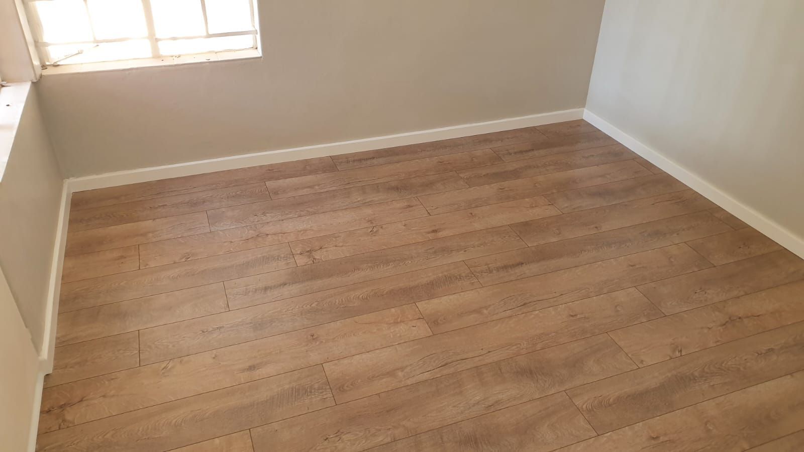An empty room with a wooden floor and a window.