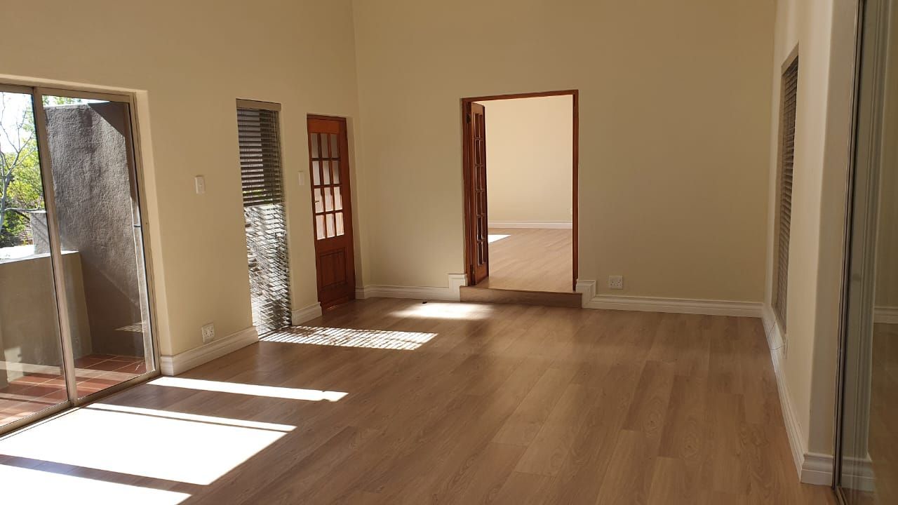 An empty room with hardwood floors and sliding glass doors