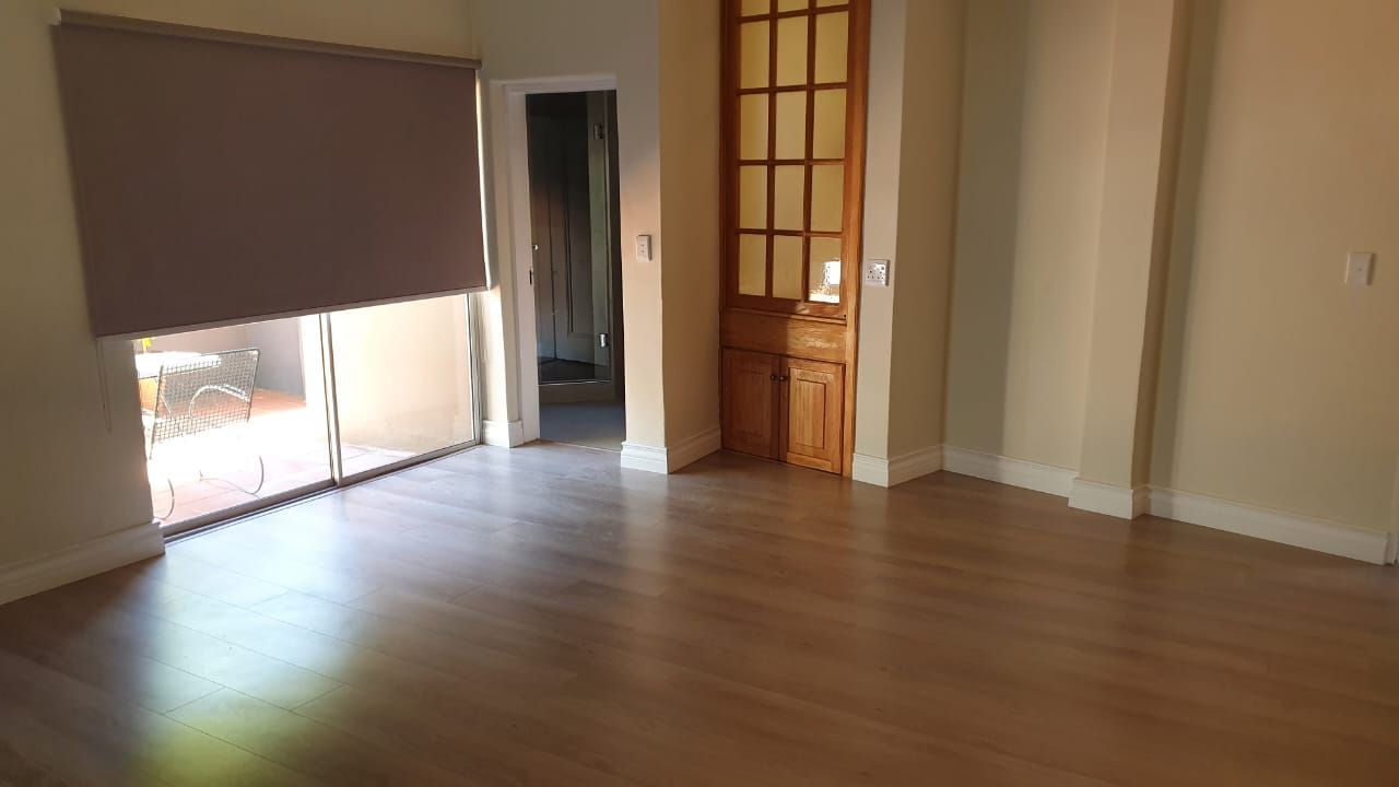 An empty living room with hardwood floors and a sliding glass door.