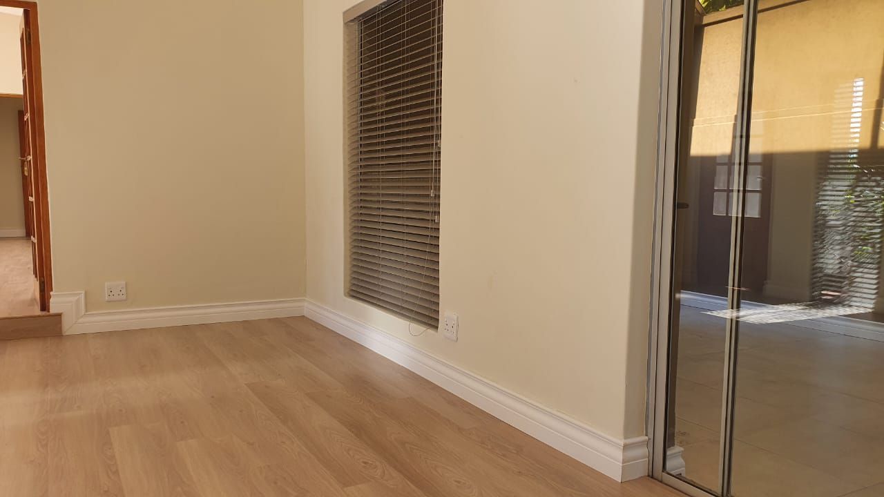 An empty room with hardwood floors and a sliding glass door.