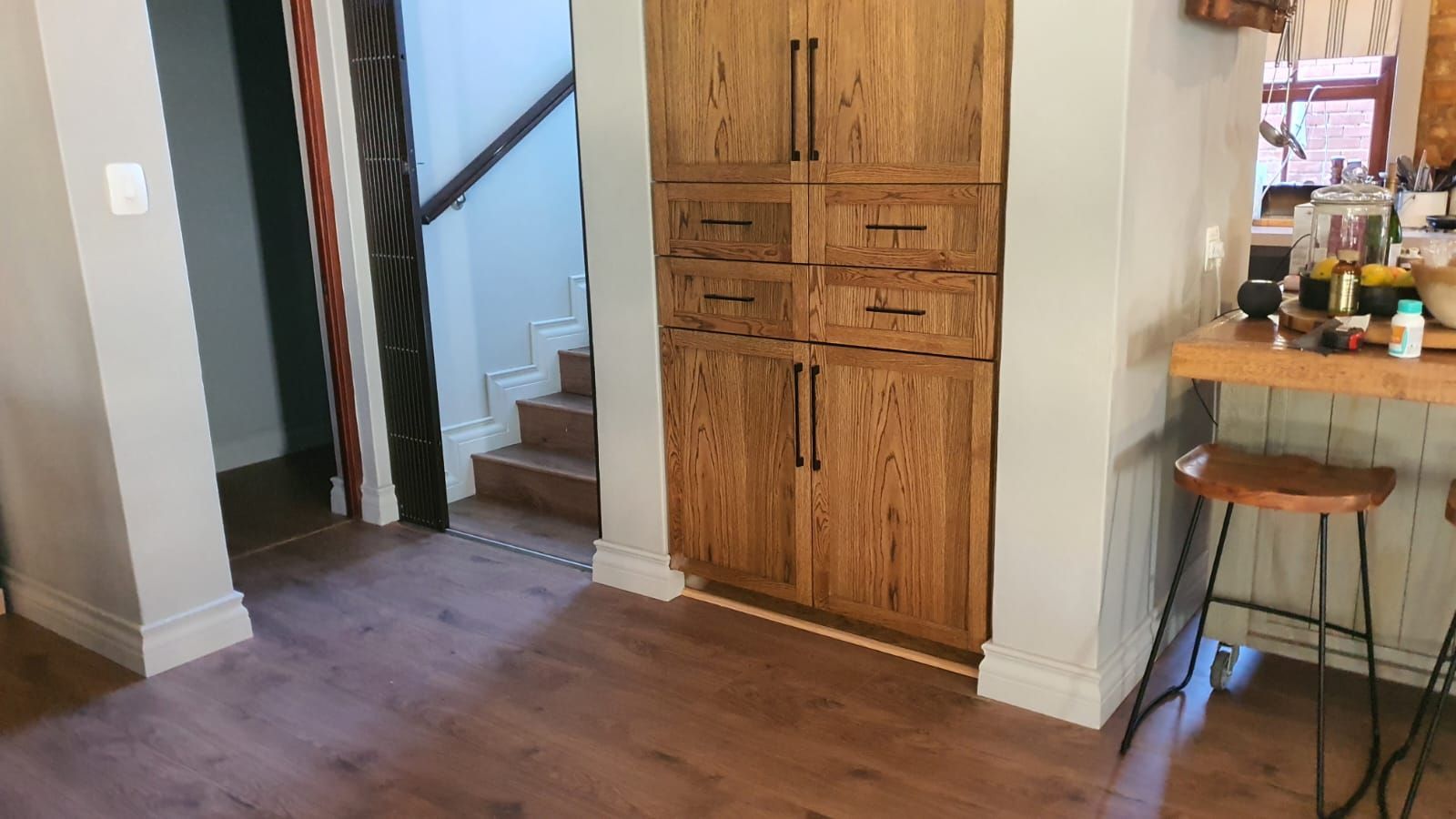 A kitchen with wooden cabinets , drawers , a bar and stairs.