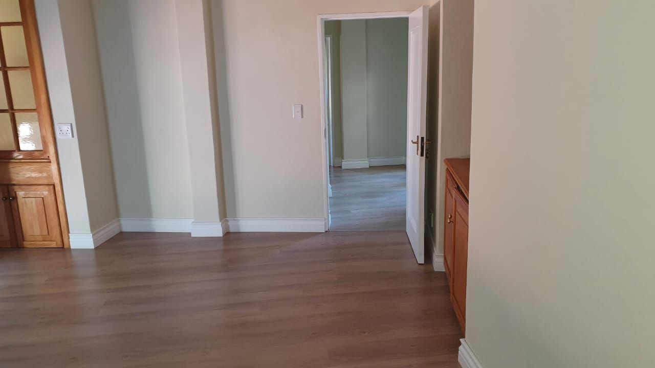 An empty room with hardwood floors and a door leading to another room.