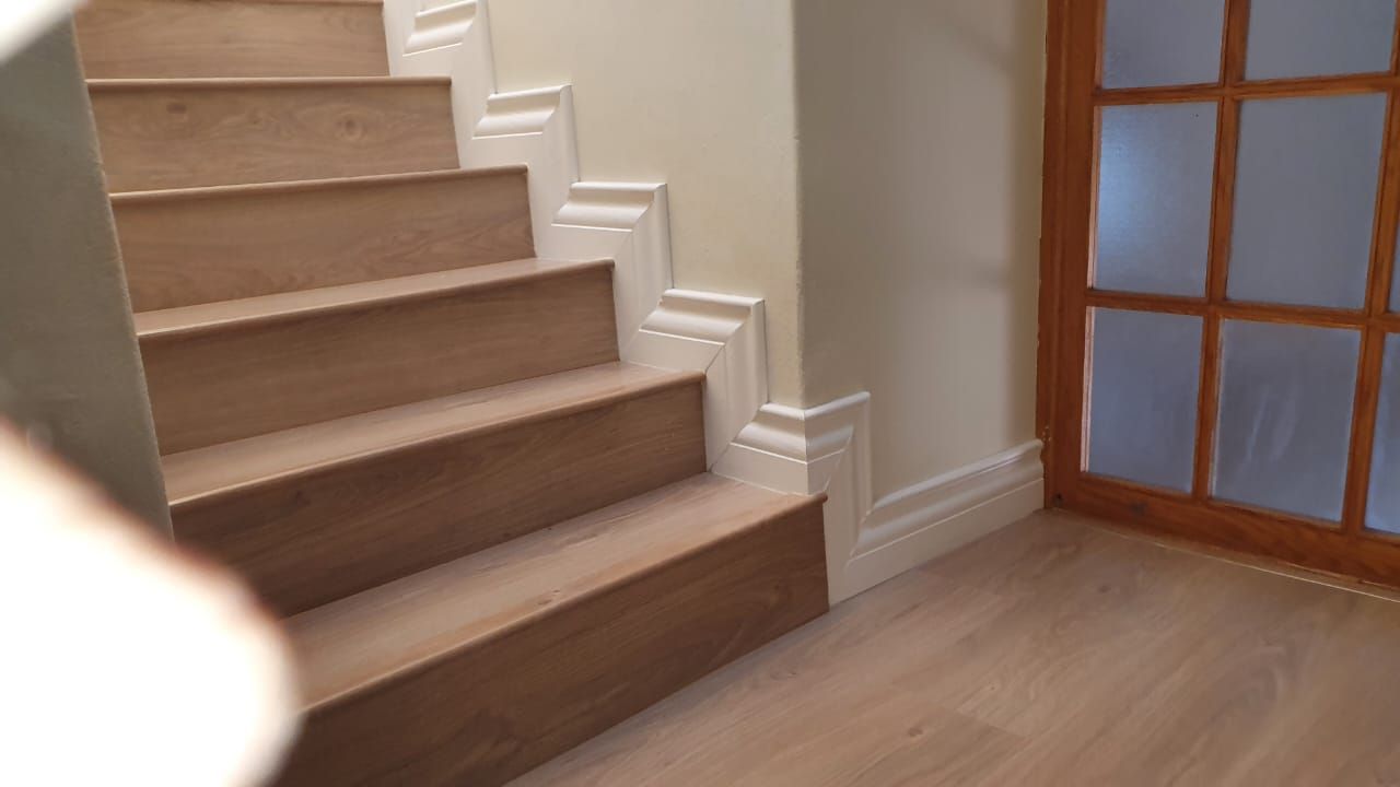 A person is standing next to a set of stairs in a room.