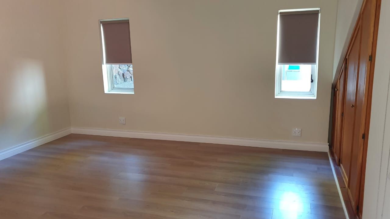 An empty room with hardwood floors and two windows.