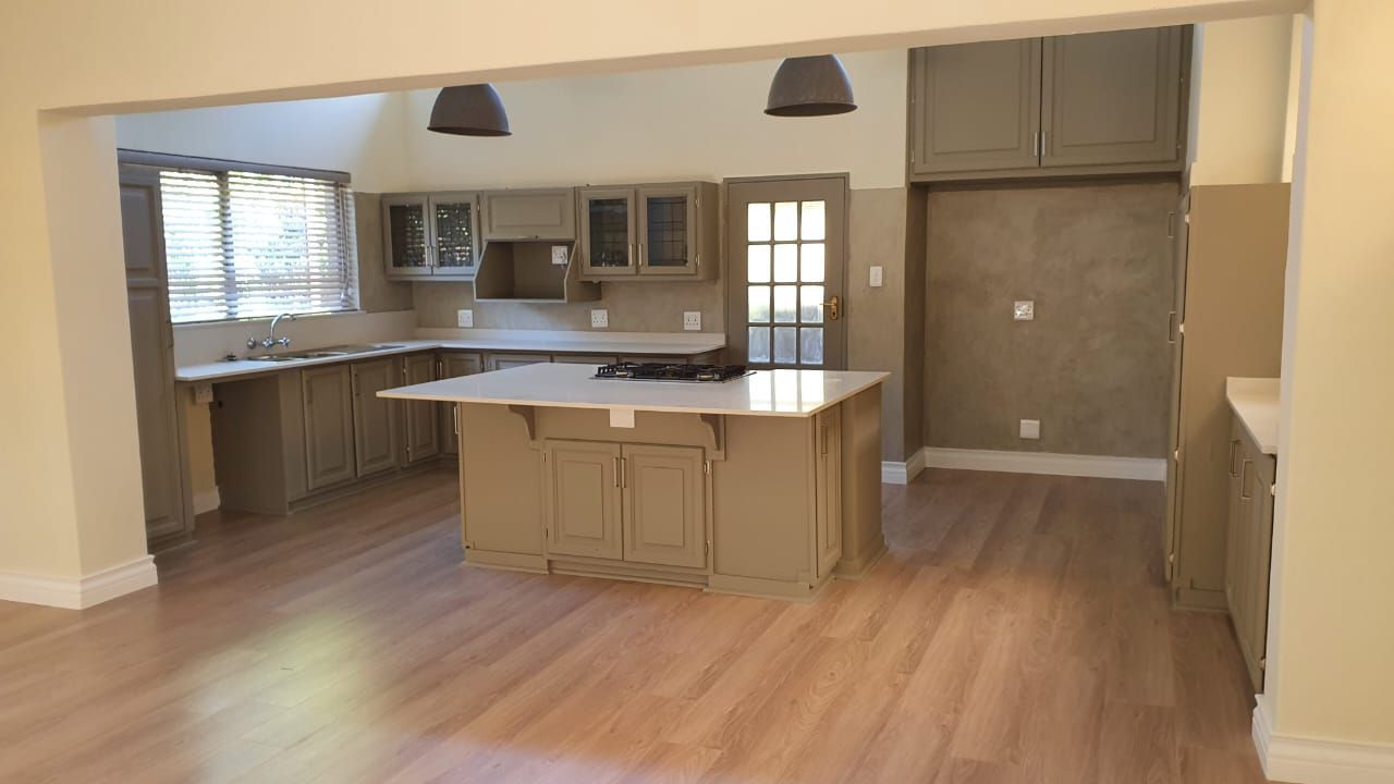 An empty kitchen with a large island in the middle of the room.