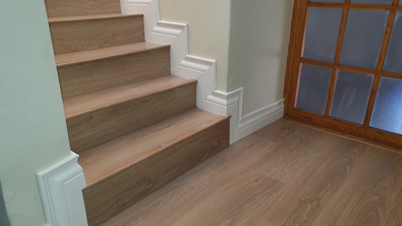 A wooden staircase with white trim and a wooden floor in a hallway.