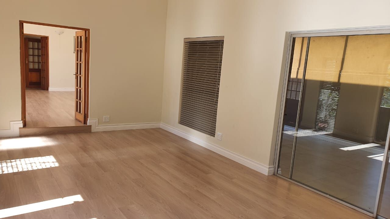 An empty room with hardwood floors and a large mirror.