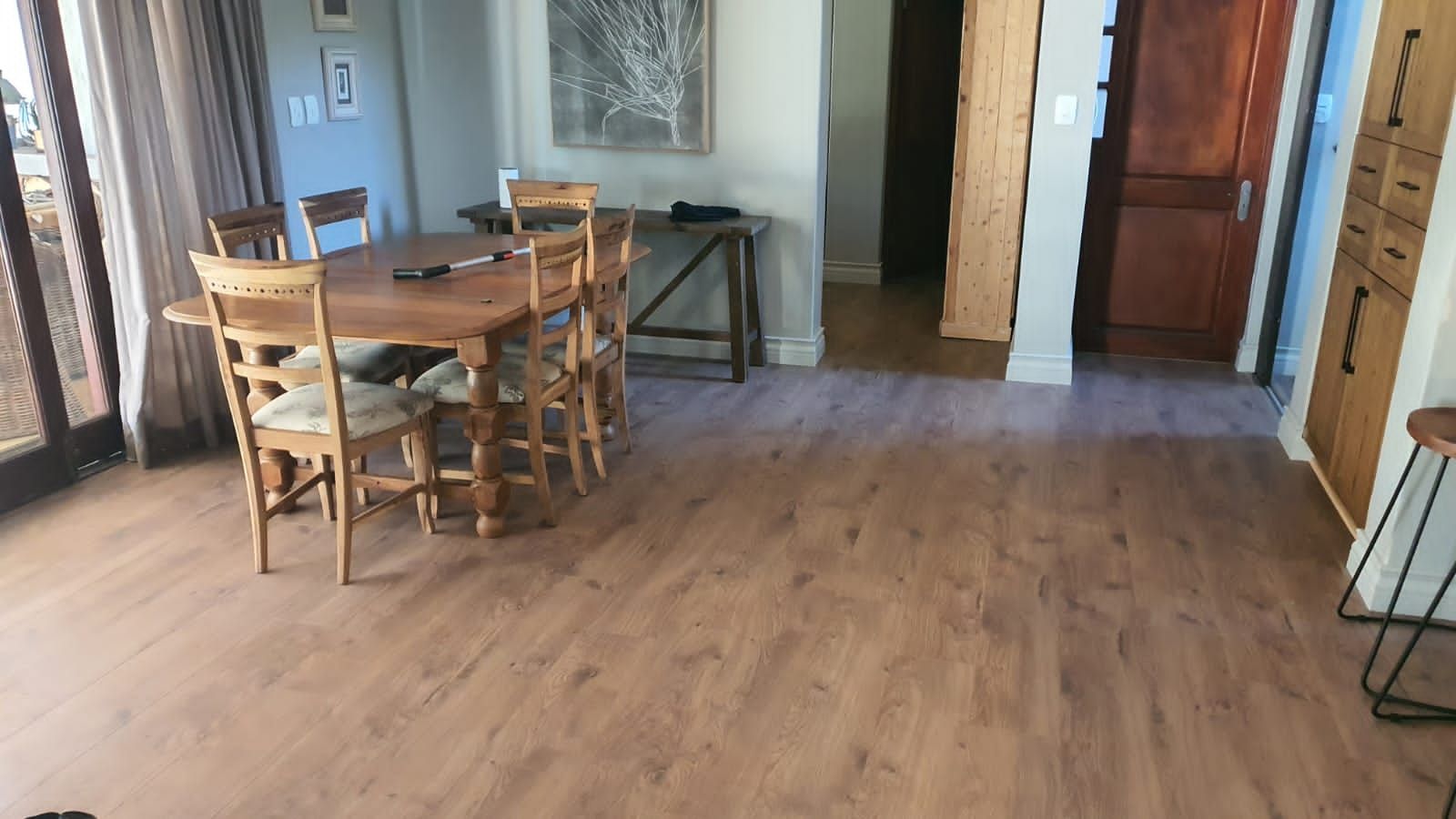 A dining room with a wooden table and chairs and a wooden floor.