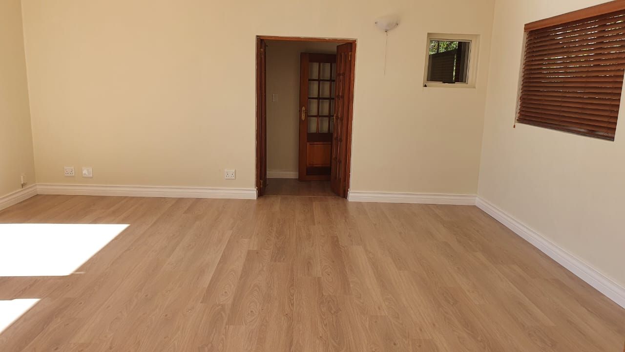An empty room with a wooden floor and white walls